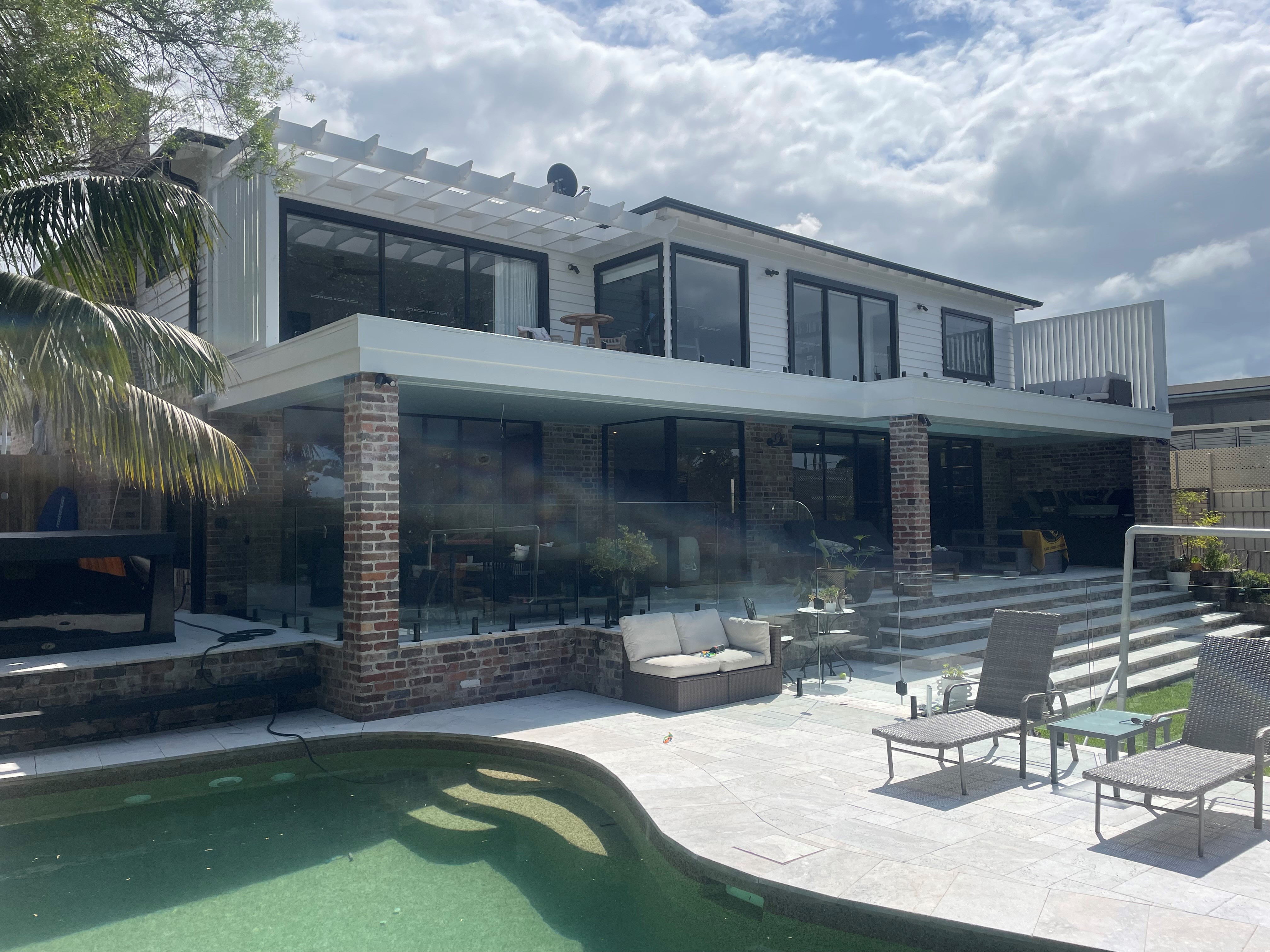 A rear finished house extension leading out into a garden and pool